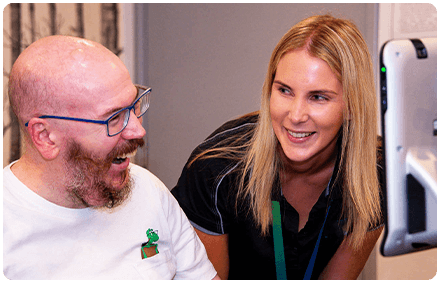 a rocky bay disability support worker and client sit together and are smiling.
