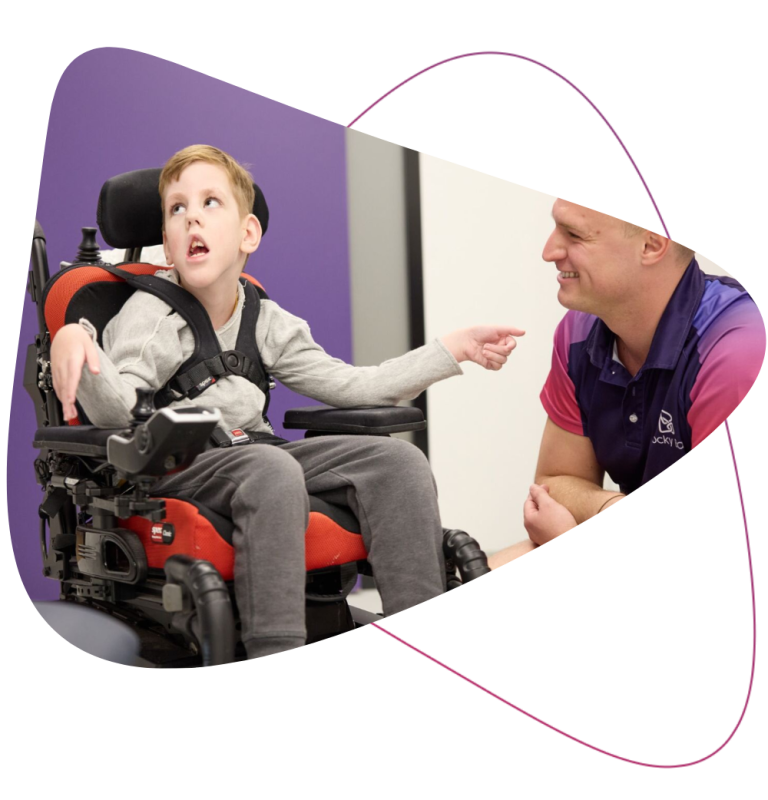 Young Rocky Bay Customer in his wheelchair with his Rocky Bay Therapist next to him smiling