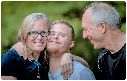 a child who lives with a disability and his parents smile and hug each other.