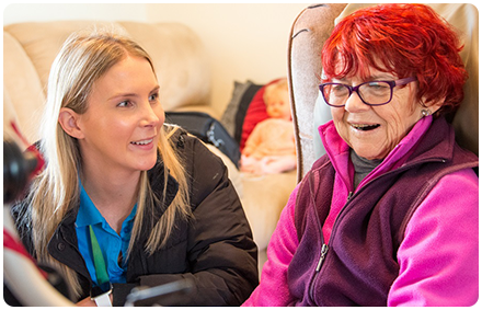 a rocky bay disability support worker and client sit together and are smiling.