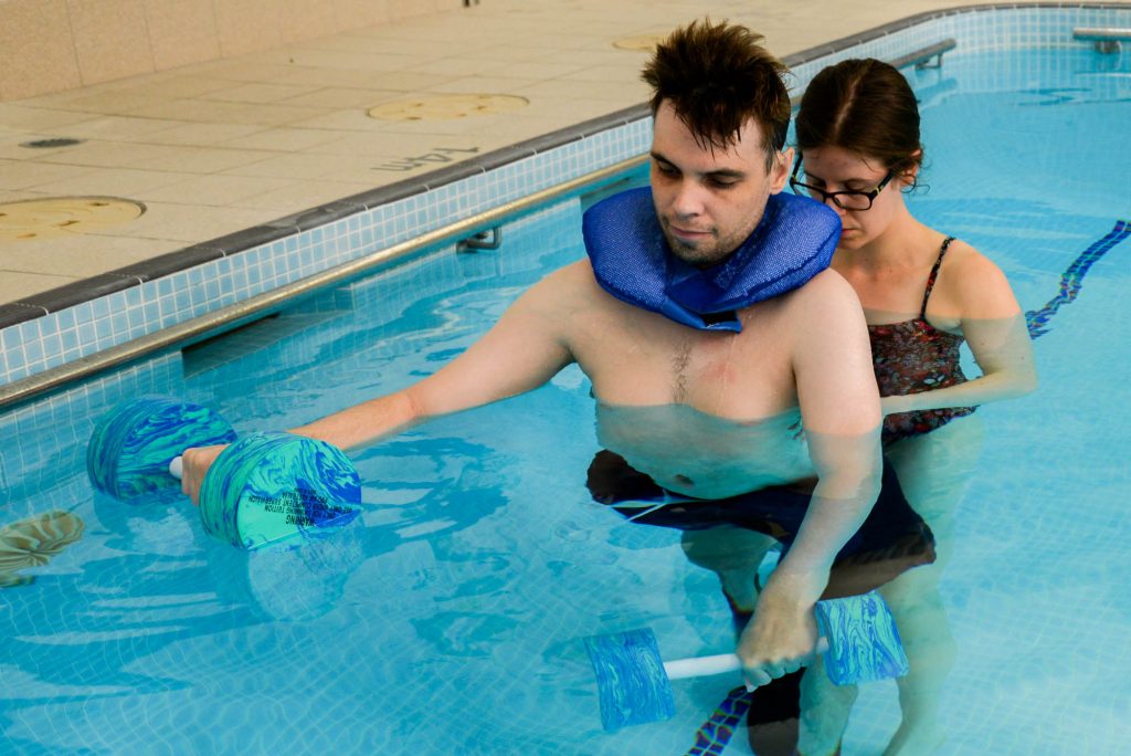 a rocky bay client is receiving hydrotherapy in a pool with his carer behind him.