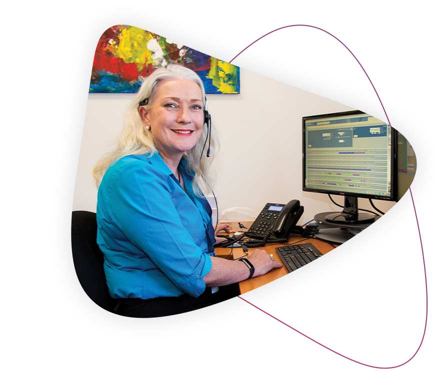 a disability support coordinator smiles at the camera while working at her desk at rocky bay.