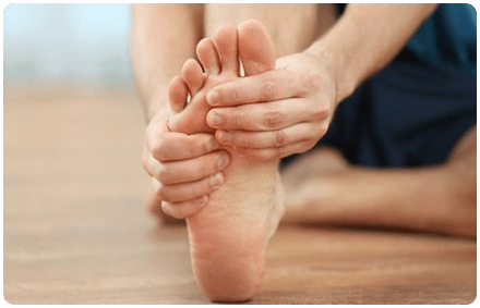 a close up image of the sole of a foot. the person gives themselves a foot massage with their hands.
