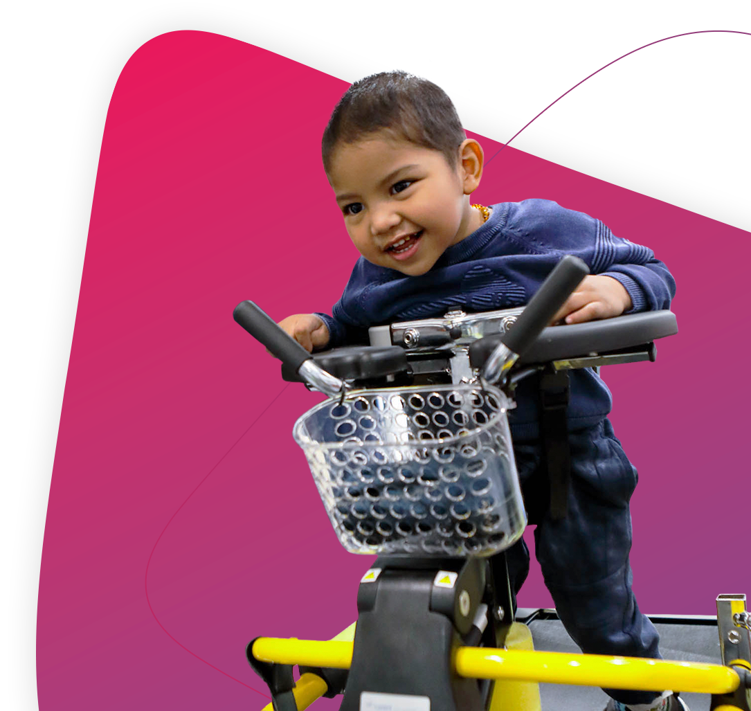 A small happy boy wearing a blue top riding on a piece of Rocky Bay equipment