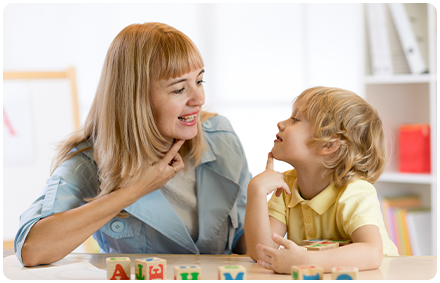 a rocky bay speech therapist treats a child in the speech clinic. they are looking at each other while sitting at a table.