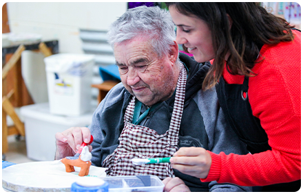 two people smile and work on art in the rocky bay art studio.