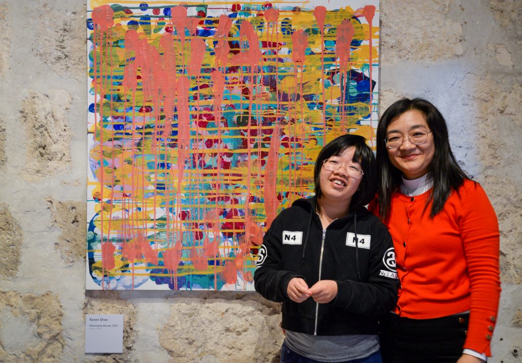 Rocky Bay artists Karen standing with her mum in front of her colourful artwork.