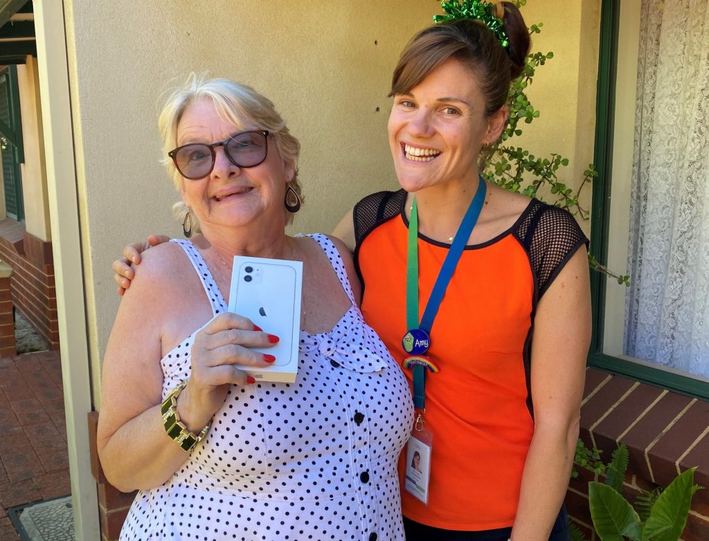 Read Peggy's story: Customer Peggy with OT Amy holding her new iPhone X from The Wishing Tree