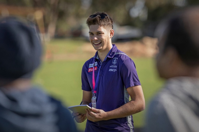 Rocky Bay's Activities Coordinator, Joel, in a purple shirt, holding a notepad and smiling