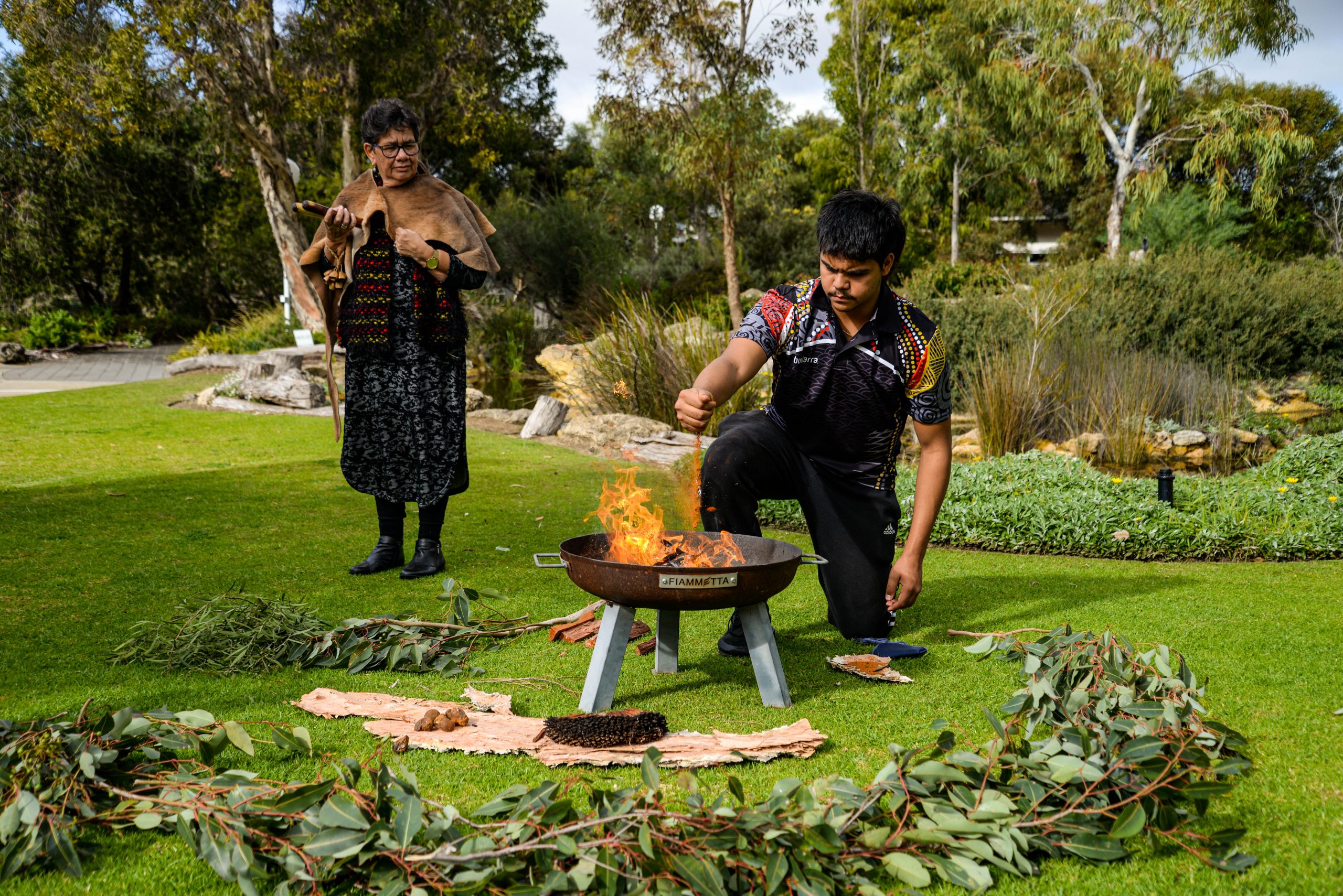 Robyn Collard and Izayah Rioli performing a smoking ceremony in the gardens of Rocky Bay's Mosman Park hub