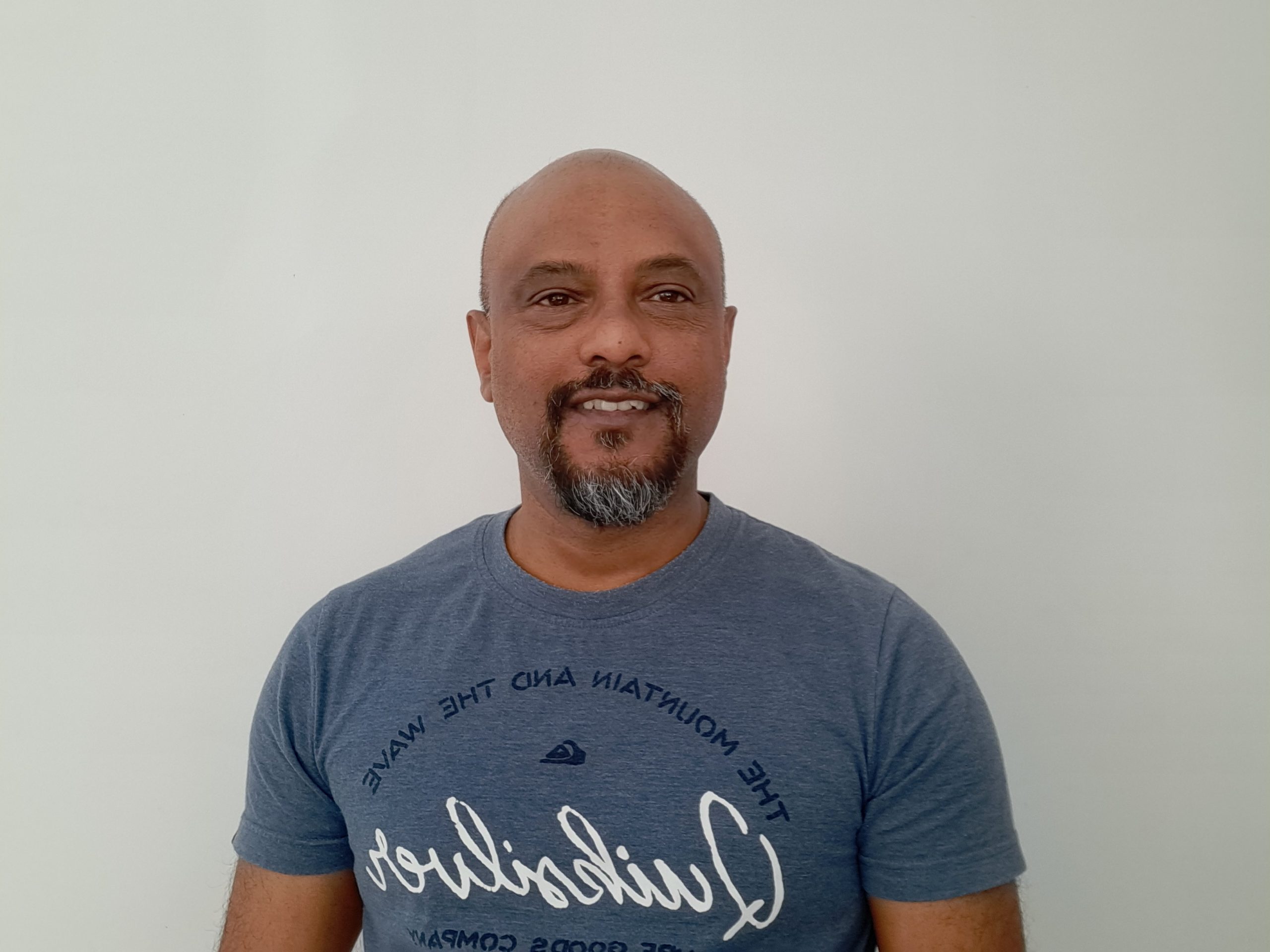 Support Worker Vikash in a blue tee shirt and smiling at the camera