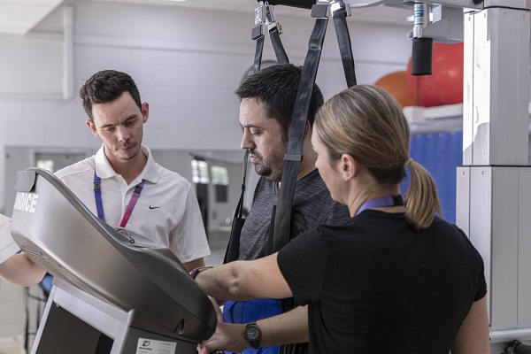 Two physoptherapists working with a customer in the gym