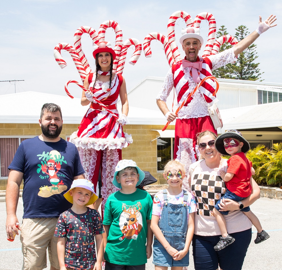 A family of five pose with two festive stilt walkers at Rocky Bay's Family Fun Day event