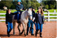 Boy with cerebral palsy rides a horse with the help of volunteers