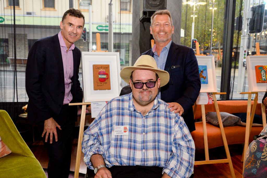 John Carey MLA, Rocky Bay artist Hamish Lamont, and CEO Michael Tait stand in front of artwork at the "Our Story" exhibition at QT Hotel