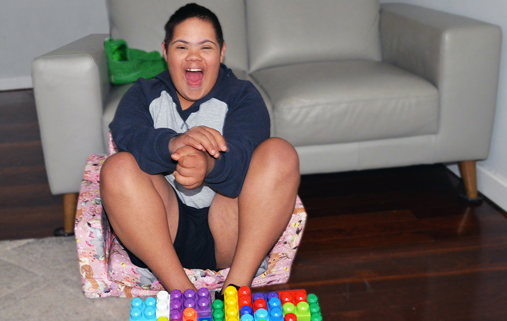 A Rocky Bay customer sitting on a small couch smiling, playing with some colourful building blocks.