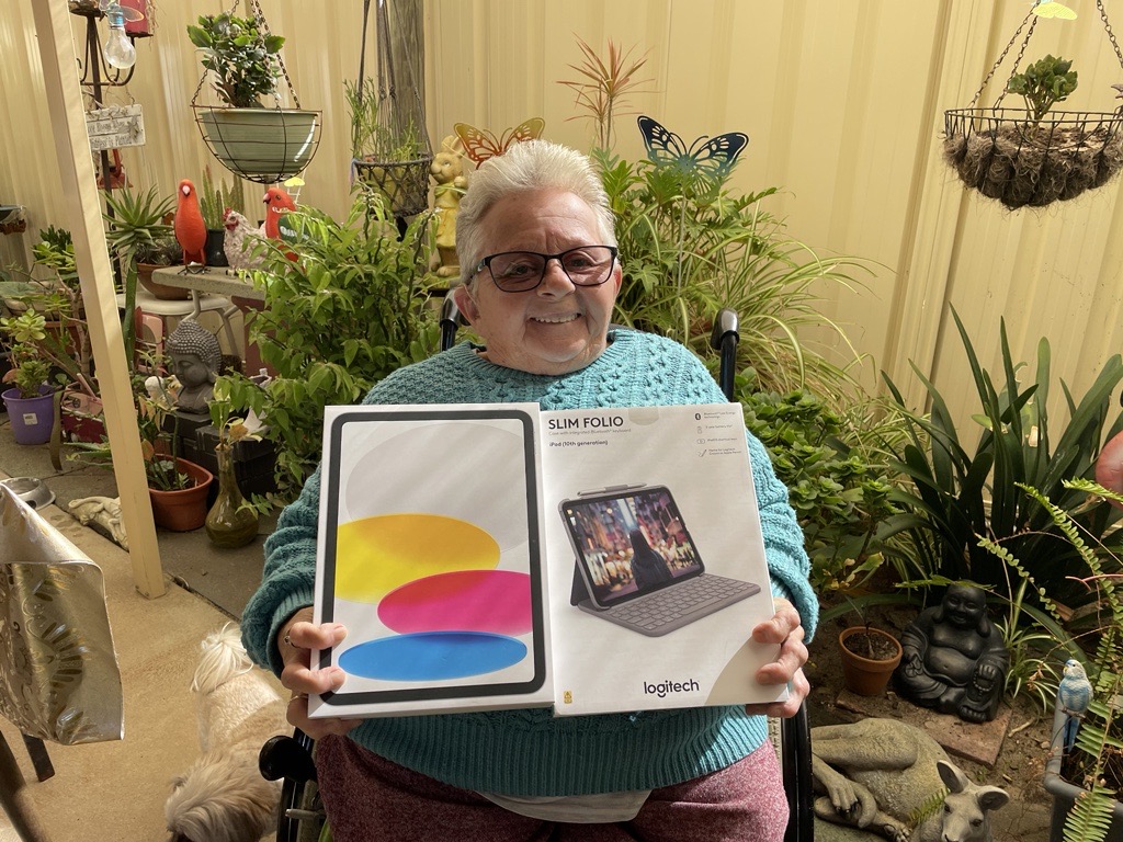 Customer Debbie smiling and holding her new iPad and keyboard.