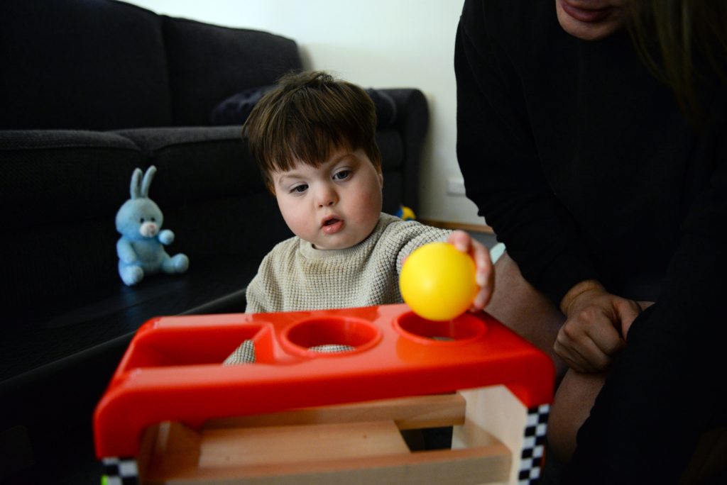 Customer Thomas engaging in therapy, placing a yellow ball into a red board.