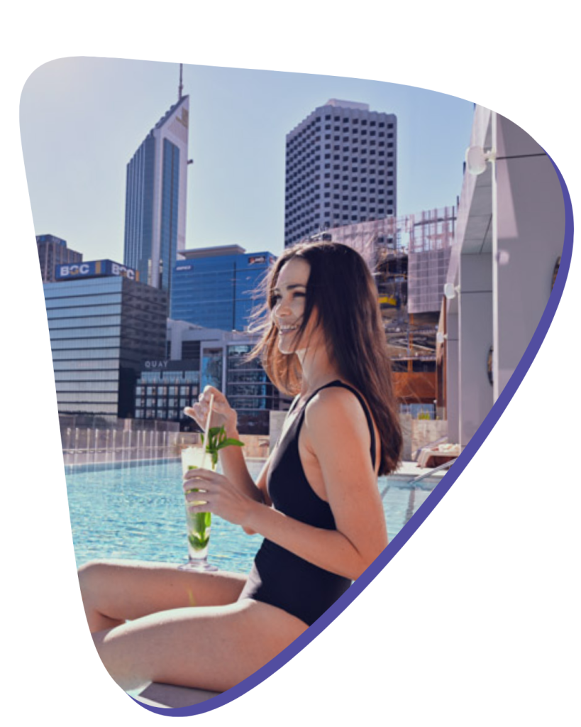 A young women sitting by the pool with a cocktail smiling