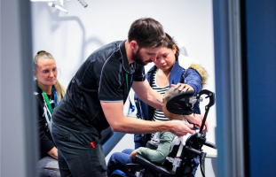 a rocky bay therapist is checking the postural support of a young boy