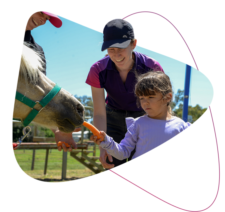 Rocky Bay customer Kennedy feeding a horse during her hippotherapy sessions.