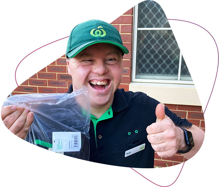 Rocky Bay customer Neil is smiling at the camera and has his thumbs up. He is wearing a woolworths uniform and holding a bag.