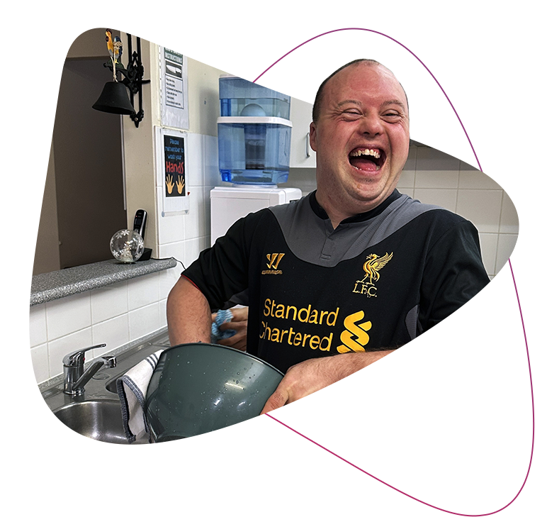 Rocky Bay customer Neil is pictured laughing as he carries out chores in his Supported Accommodation kitchen.