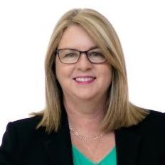 Woman in suit and glasses looks at camera smiling